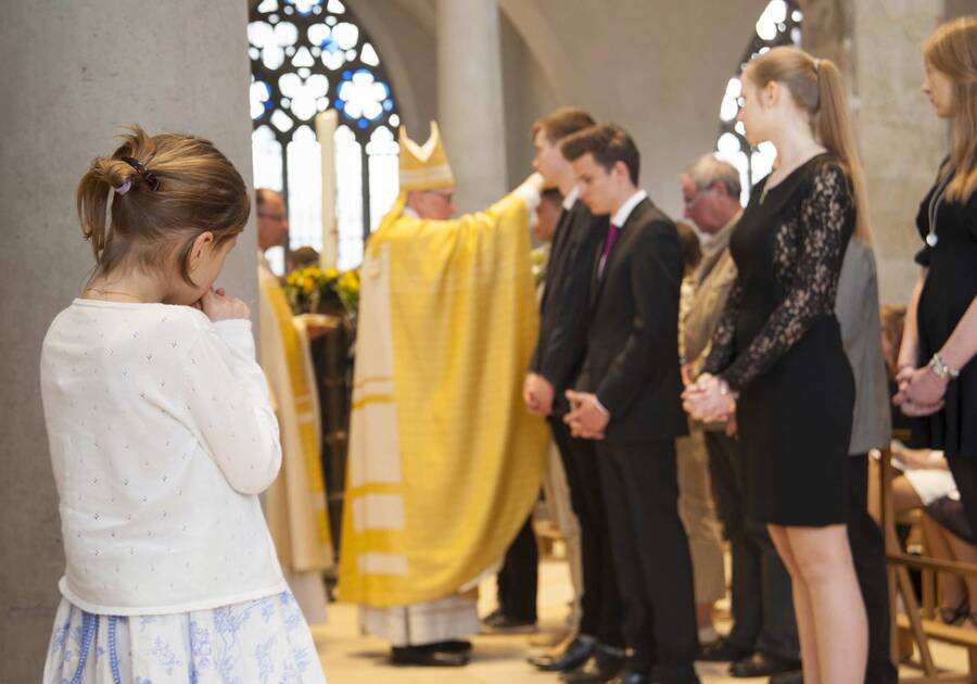 Firmungszeremonie Mädchen hinter Pfeiler, im Hintergrund Firmungszeremonie